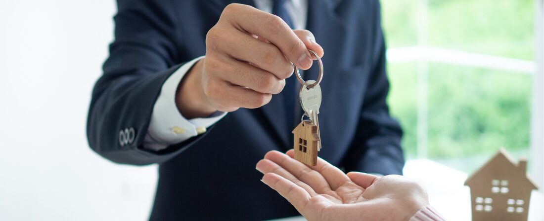 Señor entregando unas llaves con llavero de una casa a otra persona