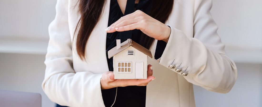 Mujer sujetando una casa pequeña entre sus manos