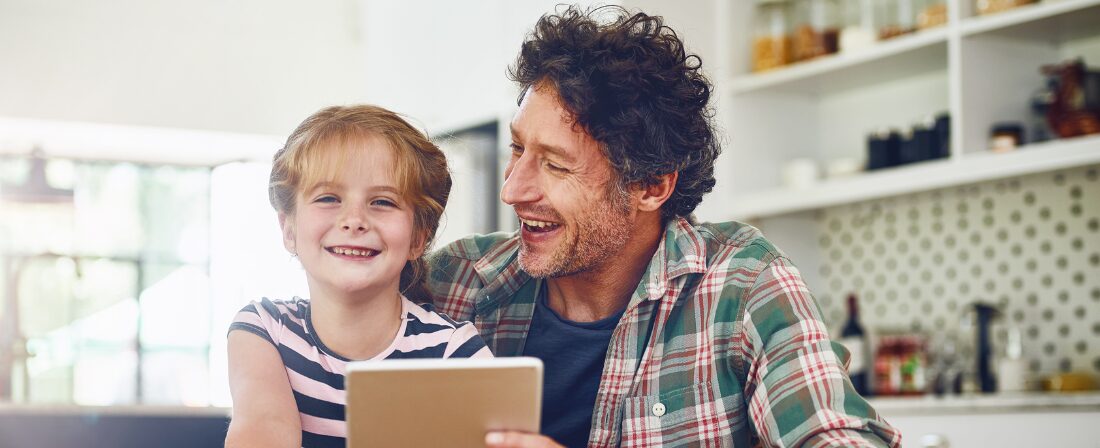 Señor con una niña riéndose mientras que sostiene algo en la mano