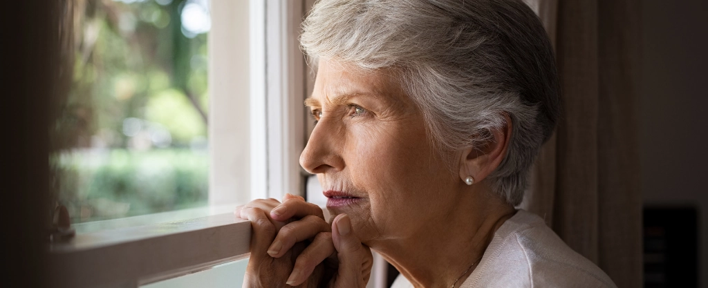 Una mujer mayor mirando por la ventana