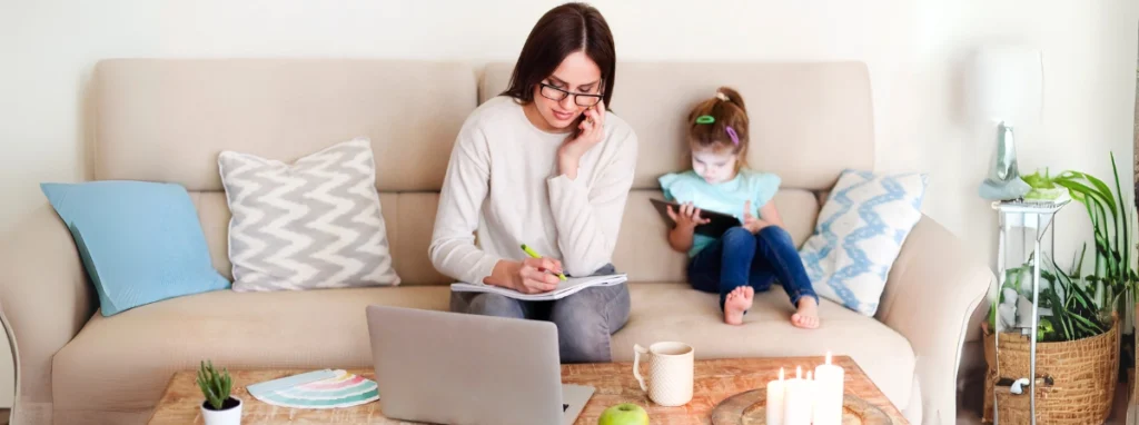 Madre trabajando con su hija en un sofá